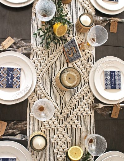 Stalas padekoruotas su žvakėmis, gėrimų padėkliukais, macrame stalo takeliu ir žalumynais